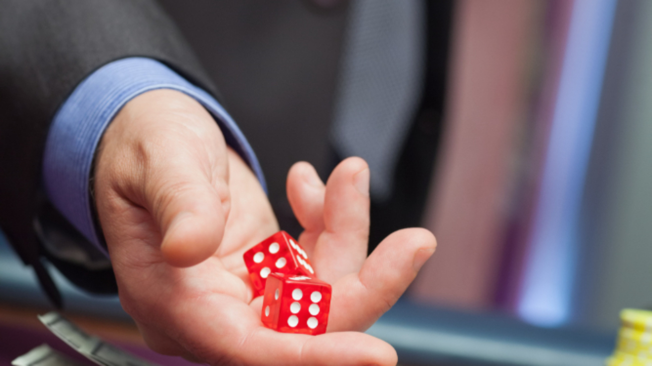 Man throwing dice on a casino table full with chips and money bills