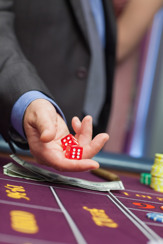 Man throwing dice on a casino table full with chips and money bills